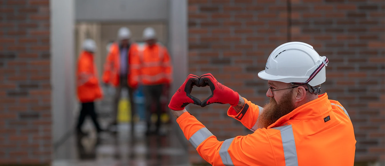 Worker on site in PPE making a heart with his hands